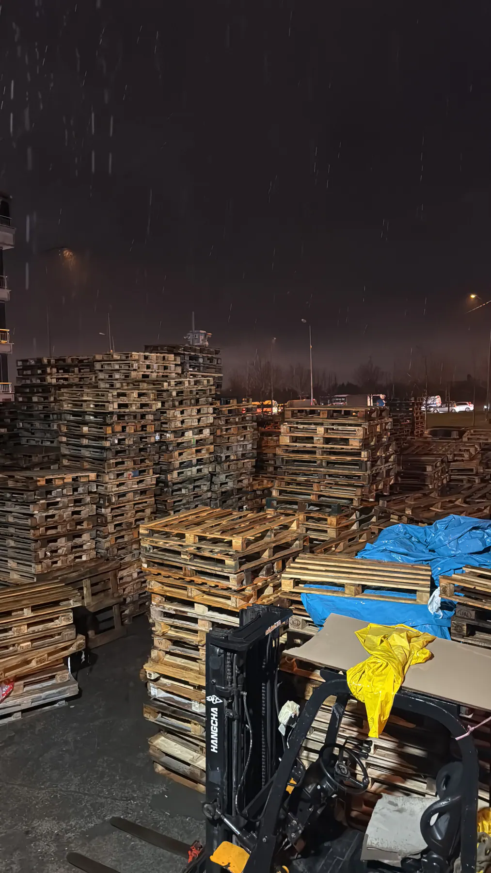 Palet stok sahasında gece devam eden forklift operasyonu